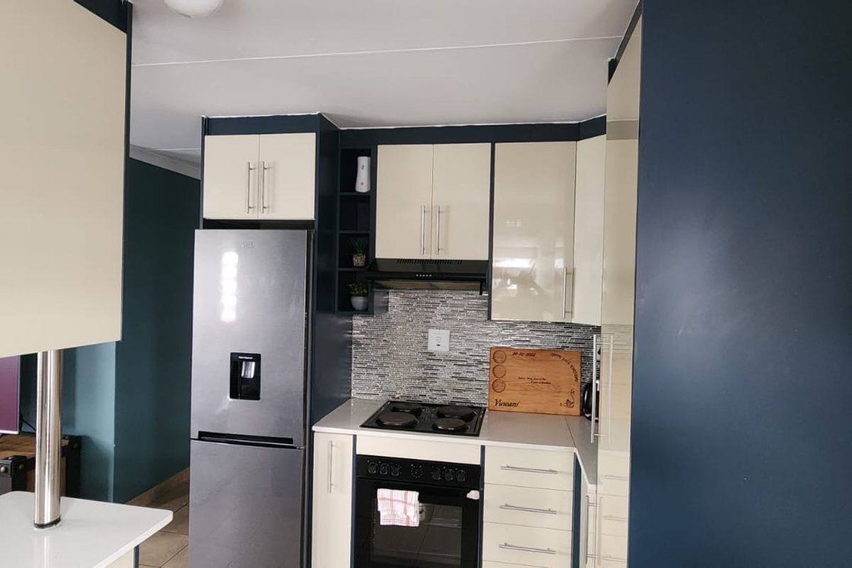 Modern kitchen featuring two-tone cabinetry, a mosaic tile backsplash, built-in oven and hob, and an integrated extractor fan.