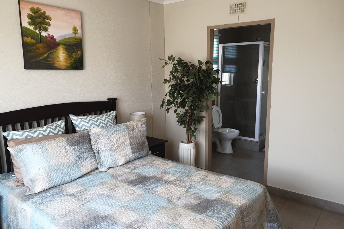 A bedroom featuring tiled flooring and an adjoining en-suite bathroom with a shower enclosure and toilet.