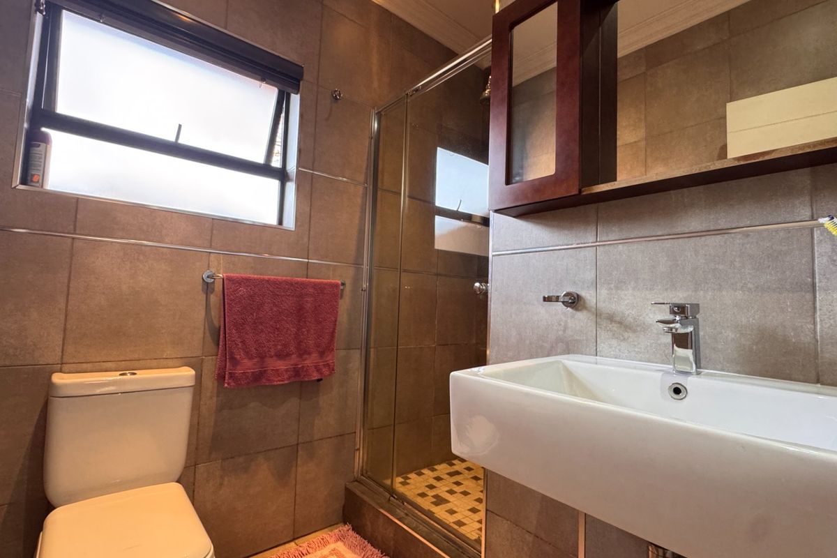 A functional bathroom featuring a shower enclosure, wall-mounted basin, and tiled finishes throughout.