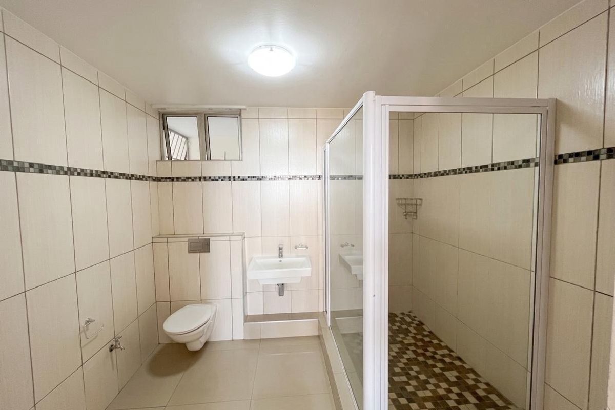 A clean, modern bathroom featuring a wall-mounted toilet, a wall-mounted basin, and a separate shower enclosure with tiled finishes throughout.