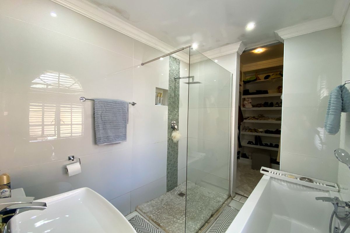 Modern bathroom featuring a walk-in shower with glass screen, freestanding bathtub, and direct access to a walk-in closet.