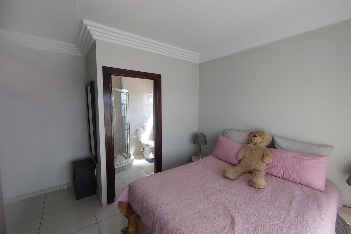 A bedroom featuring tiled flooring and crown molding, with direct access to an en-suite bathroom containing a shower enclosure.