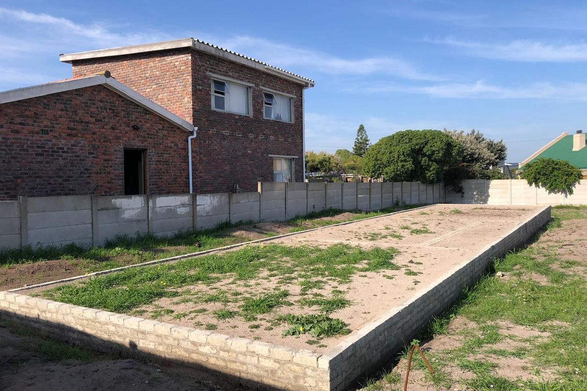 Vacant residential land featuring an exposed brick foundation slab and precast concrete boundary walling in a suburban setting.
