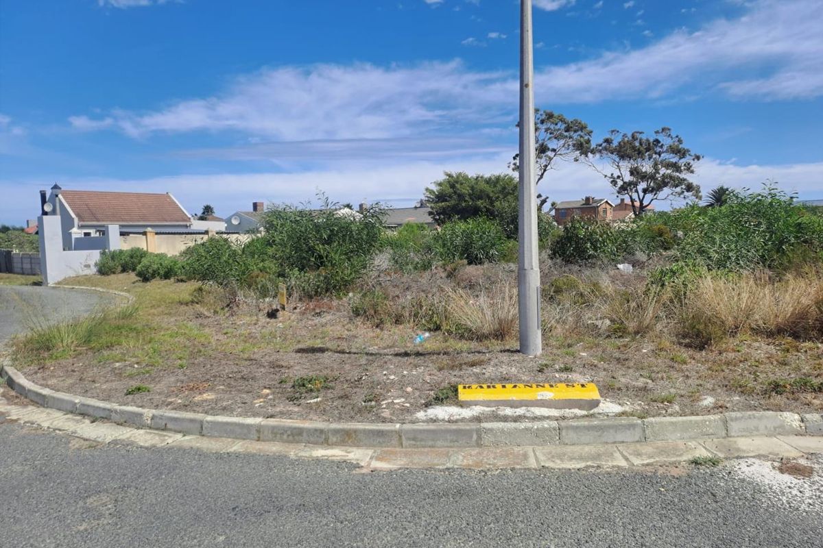 A street-level view of a vacant residential plot featuring established kerbing, a utility pole, and local street signage.