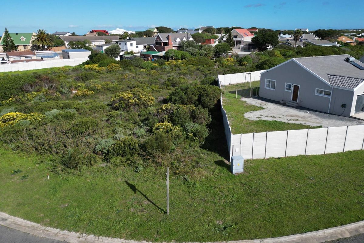Aerial view of a vacant residential plot featuring natural vegetation, enclosed by a precast concrete boundary wall in a developed neighborhood.