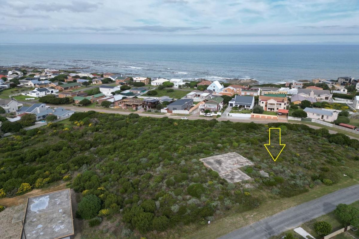 Aerial view of a vacant residential plot featuring an existing concrete slab foundation, situated in a coastal neighborhood with ocean views.