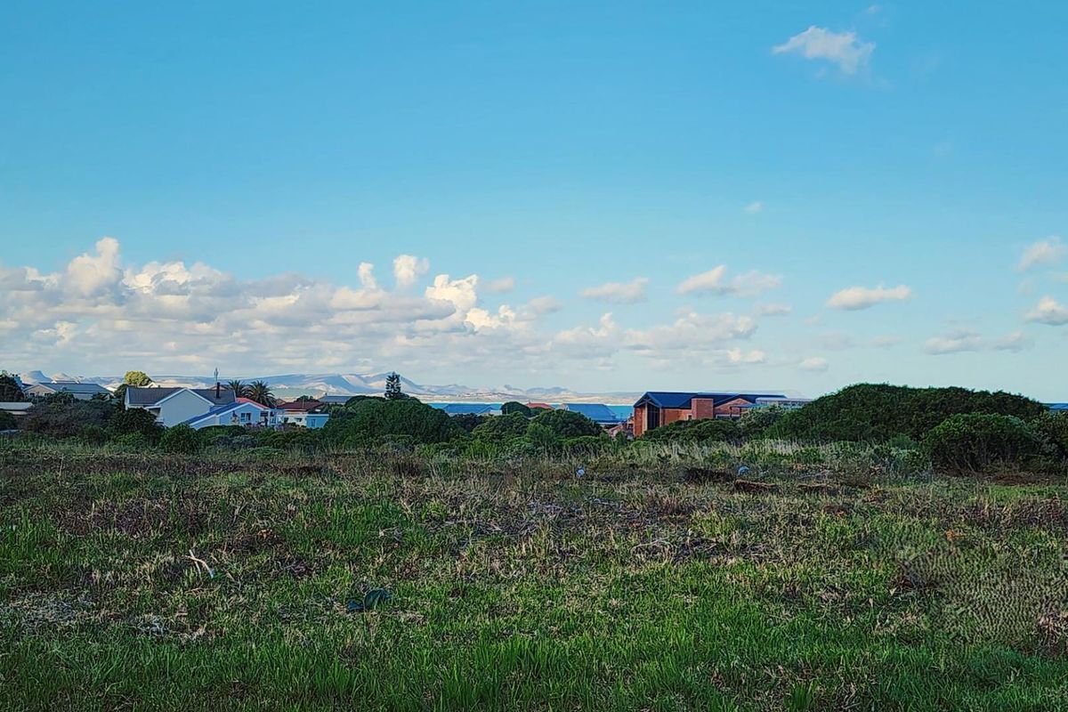 A scenic view overlooking a vacant residential plot with surrounding coastal landscape and distant mountain vistas.