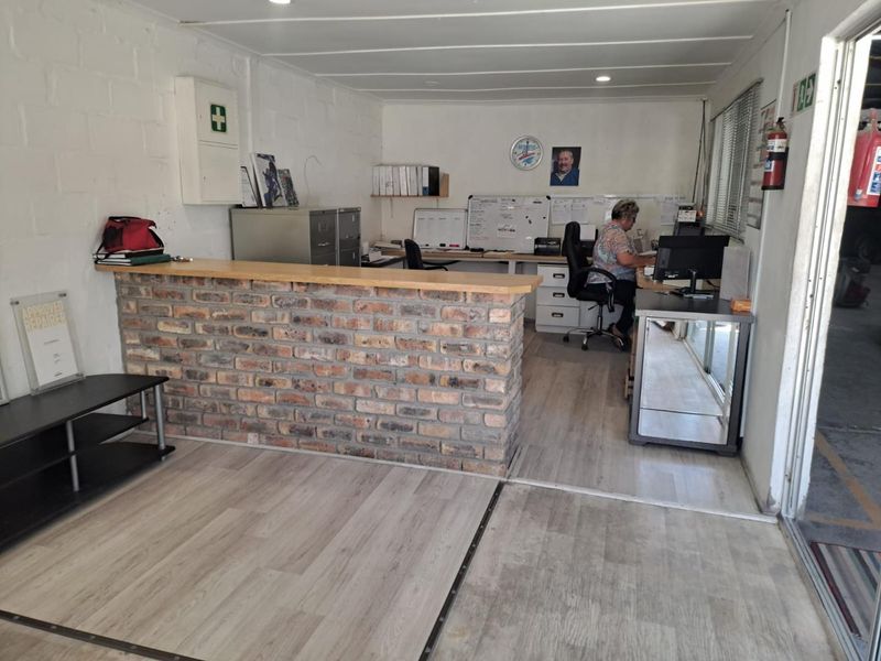 Functional industrial office space featuring a brick-faced reception counter, laminate flooring, and built-in administrative workspace.