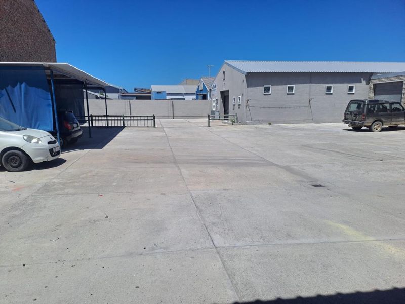 Spacious industrial concrete yard area with perimeter walling and access to adjacent warehouse structures.