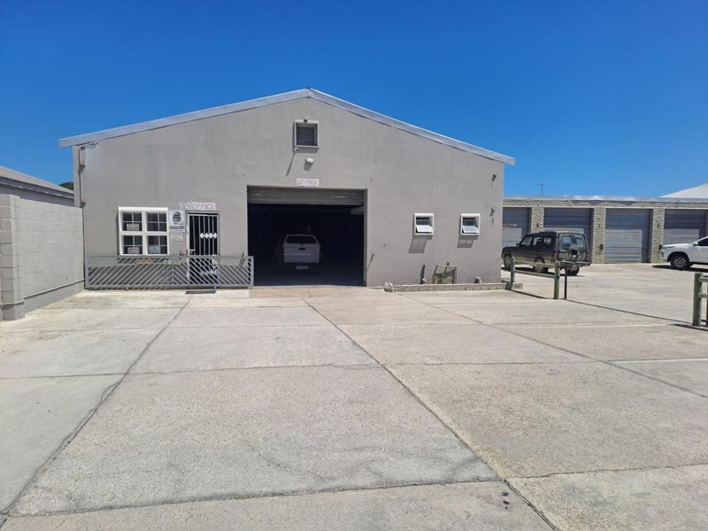 Front elevation of an industrial property featuring a large roller door entrance, office access point, and expansive concrete yard area.