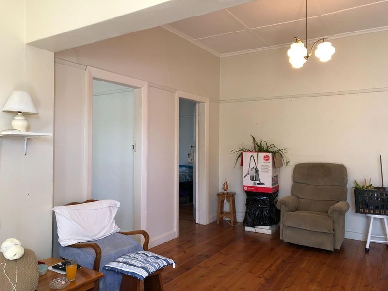 A living room featuring original timber flooring, picture rails, and neutral wall tones, offering a blank canvas for potential interior updates.