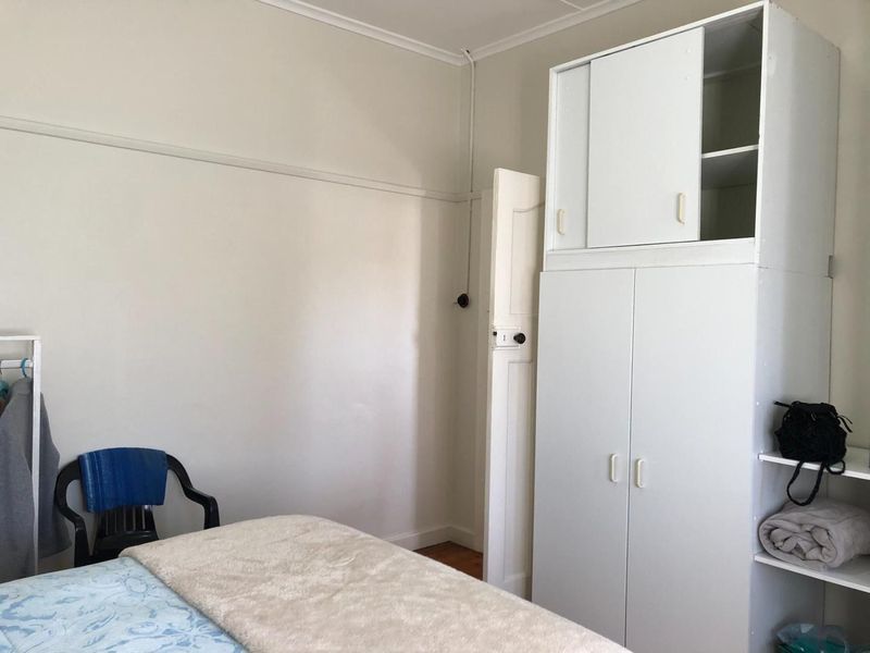 A bedroom featuring a built-in wardrobe, classic picture rail detailing, and timber flooring.