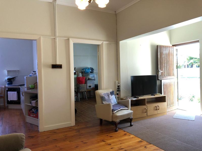 Living area featuring timber flooring and a stable-style door, with direct access to adjacent rooms and an exterior entrance.