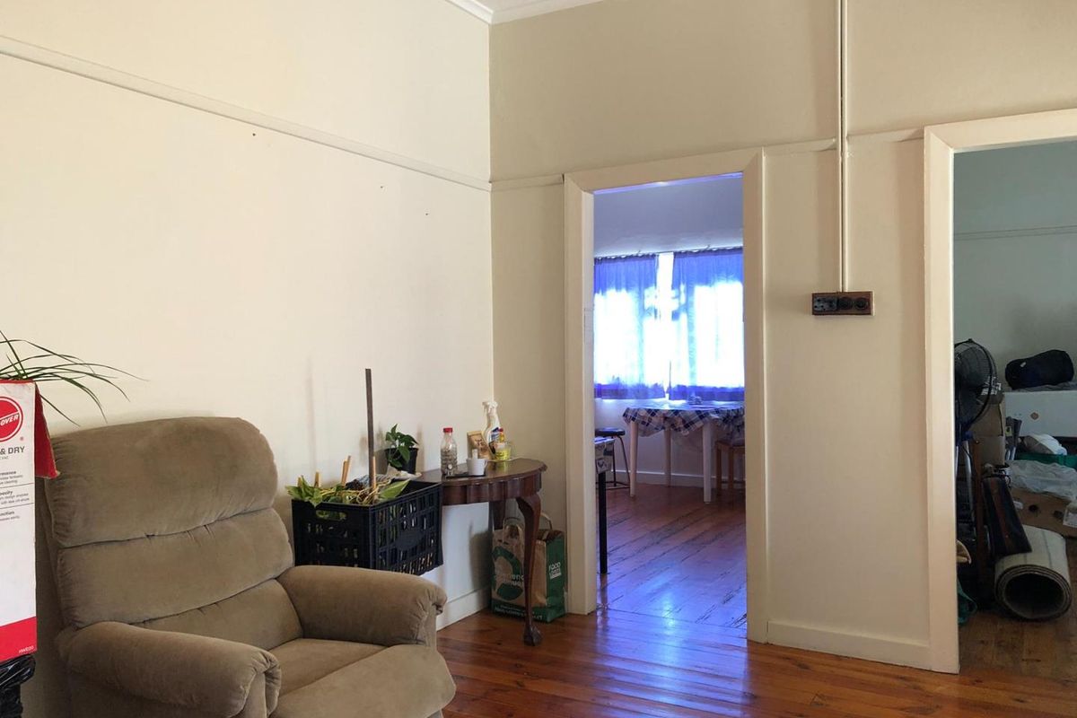 Living room featuring original timber flooring and picture rails, with an open doorway leading to an adjacent room.