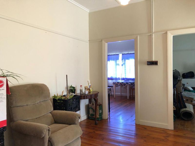 Living room featuring original timber flooring and picture rails, with an open doorway leading to an adjacent room.