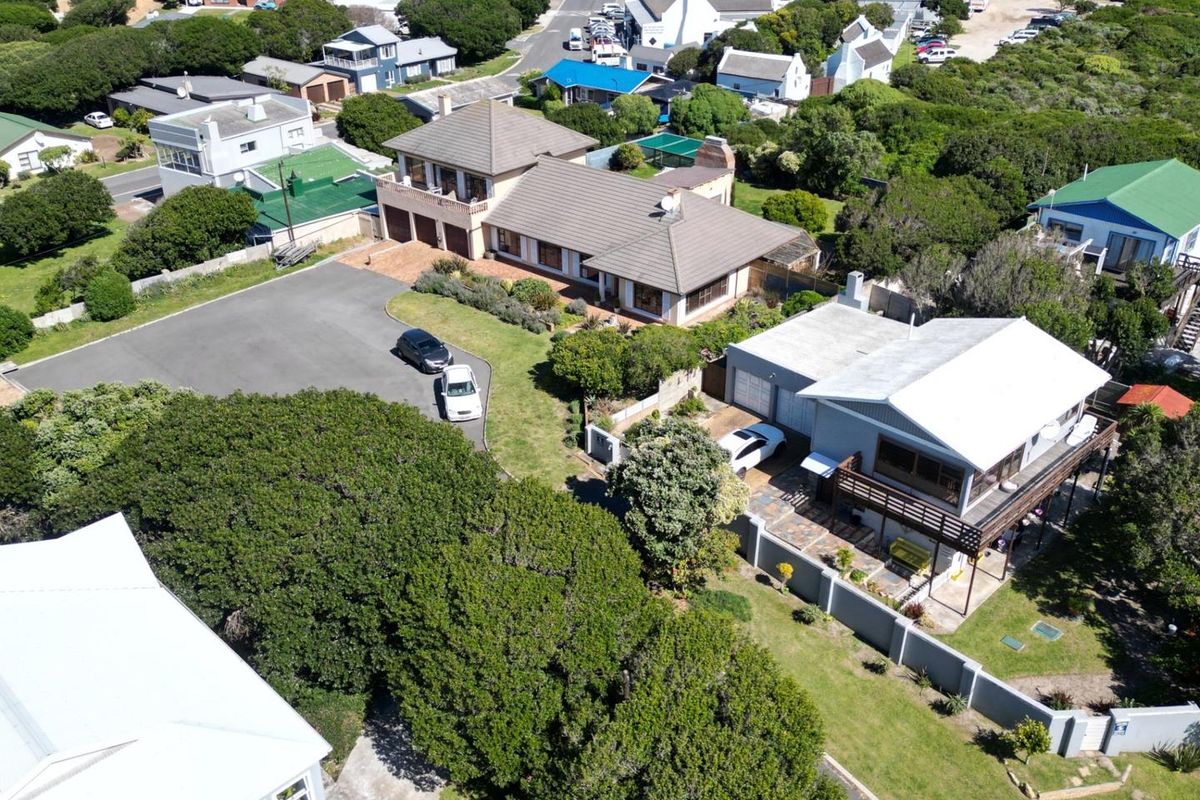 Aerial view of the property showing the main house, driveway, surrounding garden, and neighbouring residential area.