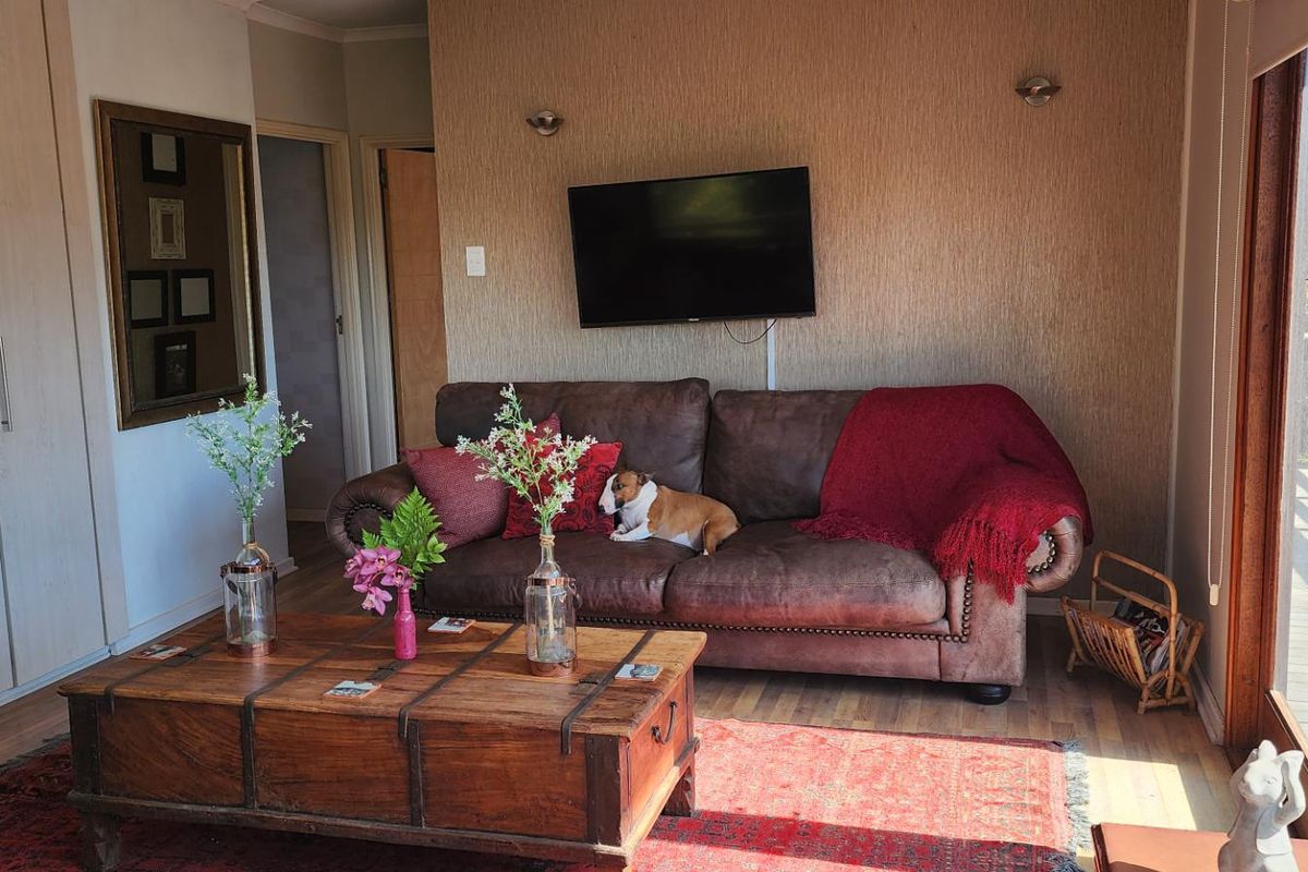 A comfortable living room featuring built-in storage cupboards, laminate flooring, and a sliding glass door providing access to an outdoor area.