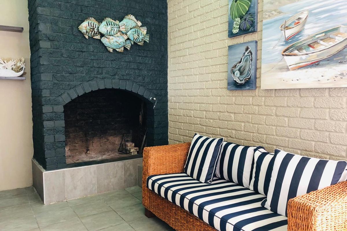 A cozy living area featuring a prominent dark-painted brick fireplace and neutral tiled flooring, creating a warm and inviting atmosphere.
