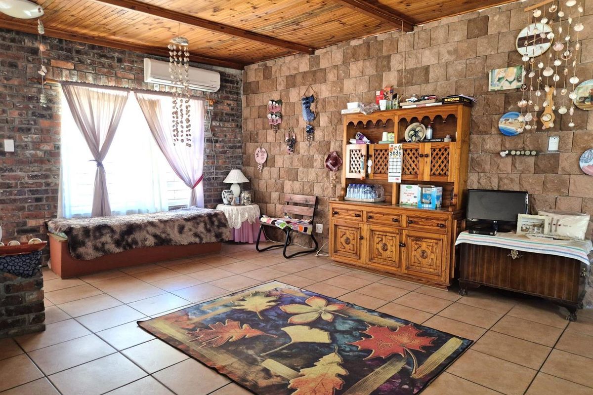 Living room featuring exposed brick and stone feature walls, timber ceiling, and tiled flooring, providing a rustic aesthetic.