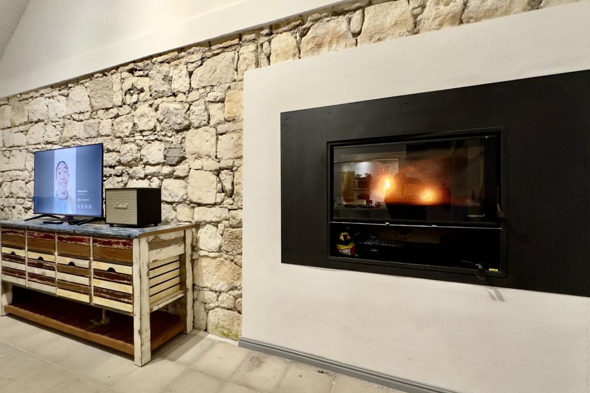 A cozy living area featuring a prominent natural stone wall and a modern built-in fireplace, creating a warm and inviting atmosphere.