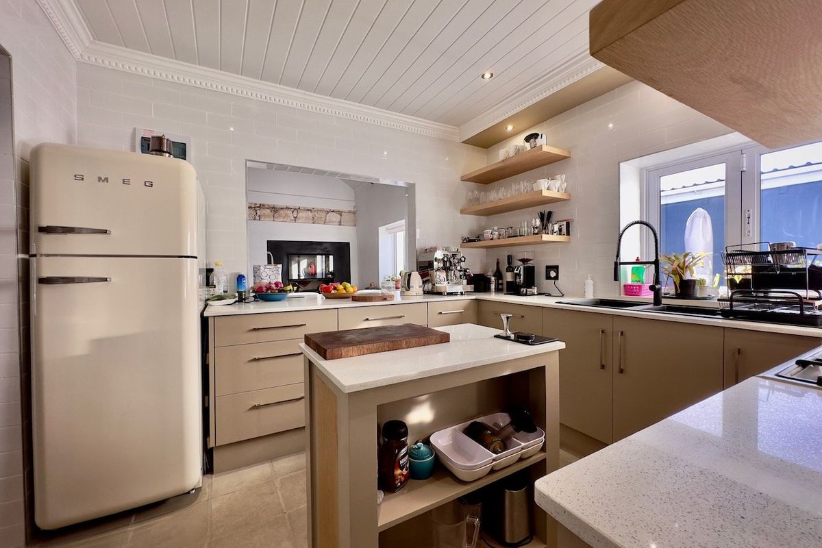 Modern kitchen featuring stone countertops, subway tile backsplash, floating shelving, a central island, and a tongue and groove ceiling with recessed lighting.