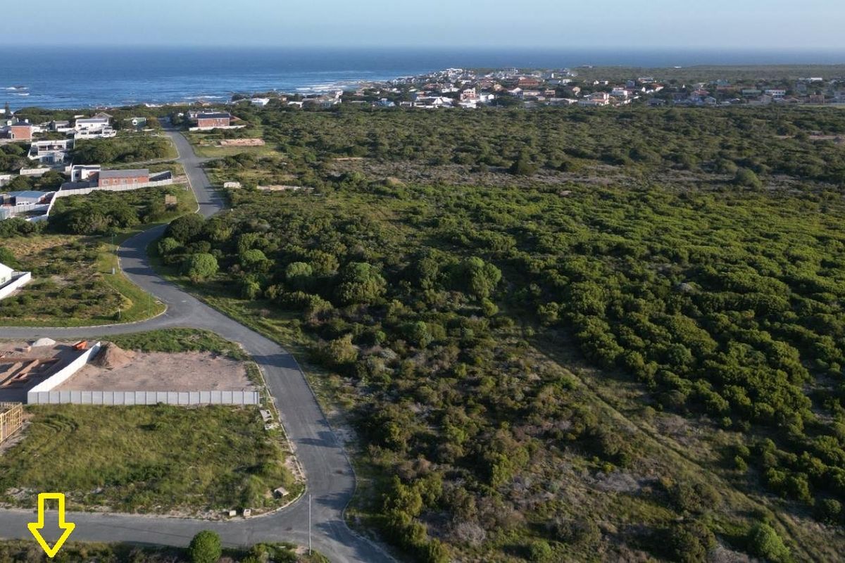 Aerial view of a residential plot in a coastal neighborhood, showing surrounding infrastructure, vegetation, and proximity to the ocean.