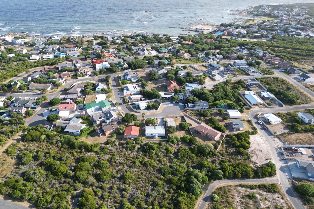 An aerial view of a coastal residential neighborhood, showcasing the surrounding landscape, street layout, and proximity to the ocean.