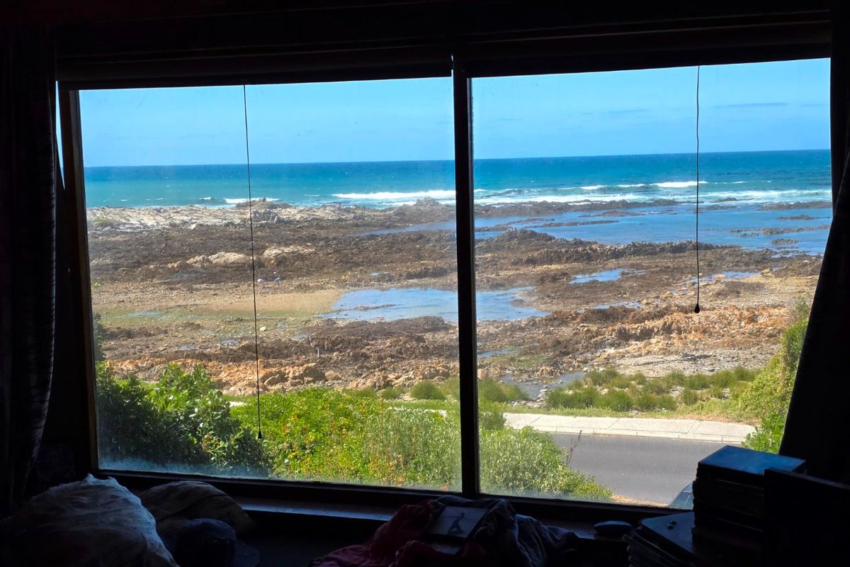 A scenic view of the rocky coastline and ocean captured through a large picture window.