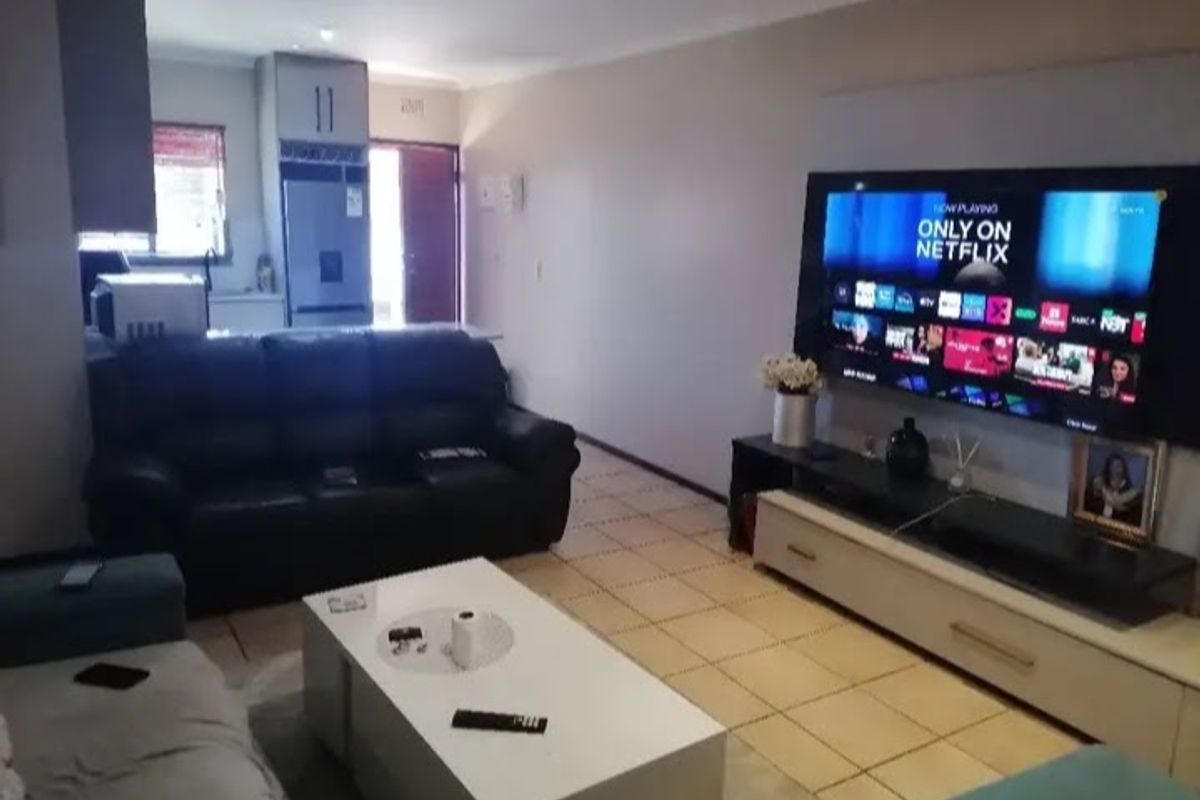 Open-plan living area featuring tiled flooring and recessed lighting, seamlessly connected to a functional kitchen space.