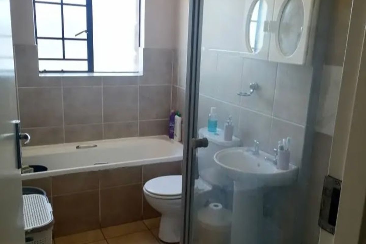 A functional bathroom featuring a bathtub, pedestal basin, toilet, and a separate shower enclosure with tiled finishes throughout.