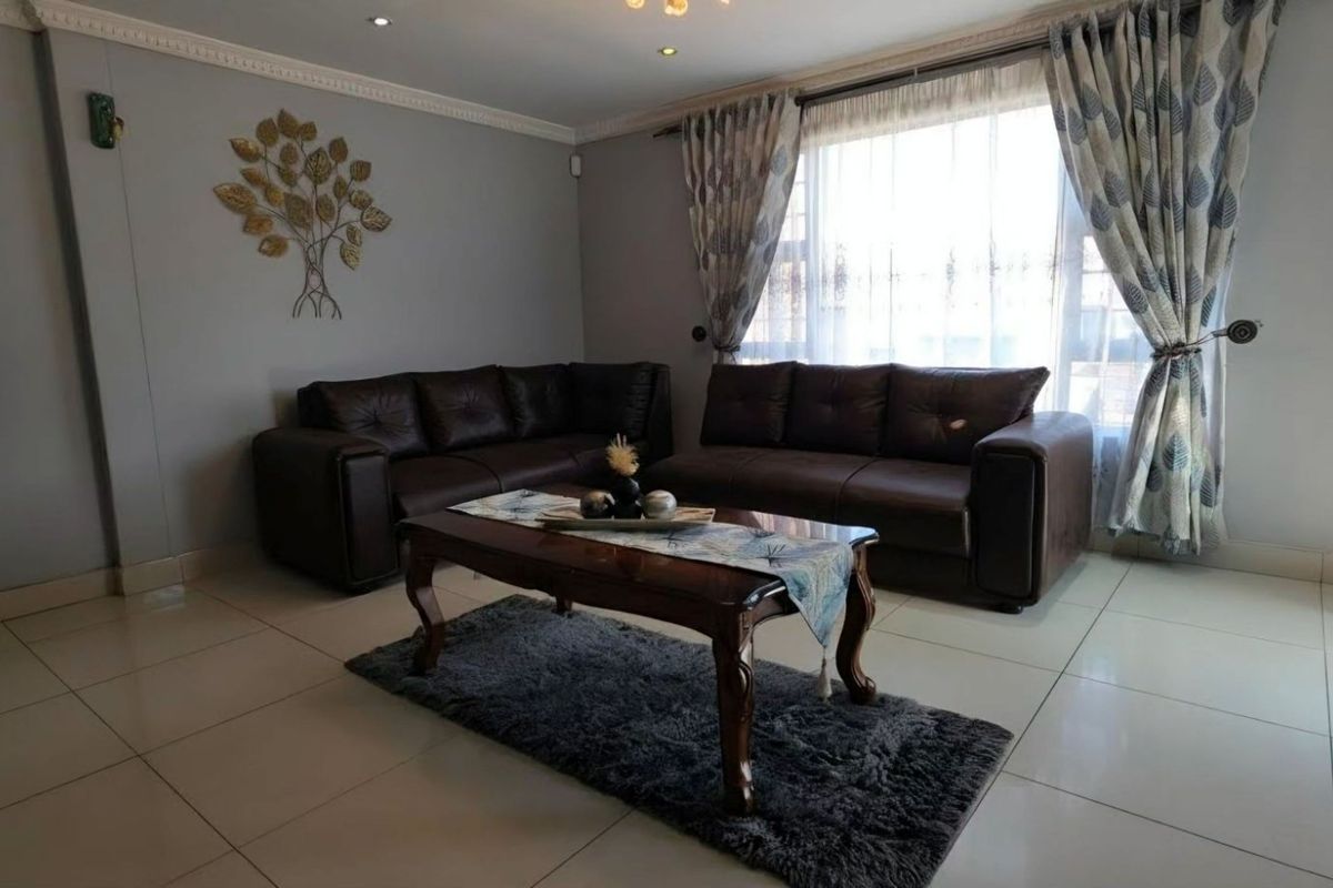 A well-maintained living room featuring neutral tiled flooring, recessed downlighting, and decorative crown molding, providing a comfortable and bright living space.