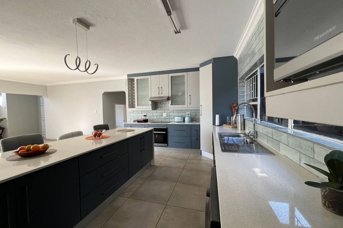 Modern kitchen featuring a large central island, quartz countertops, subway tile backsplash, and integrated appliances with a clean, contemporary finish.