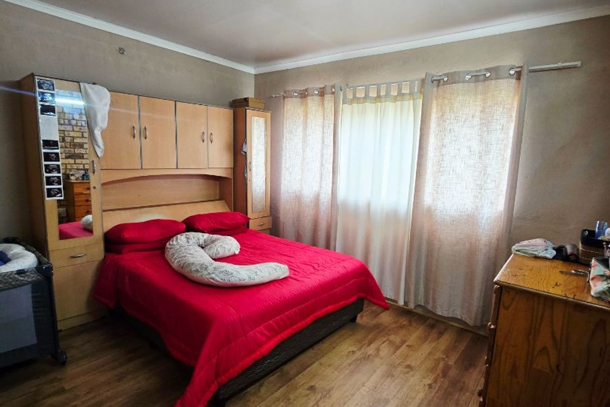 A bedroom featuring laminate flooring, coved ceilings, and a built-in wardrobe unit.