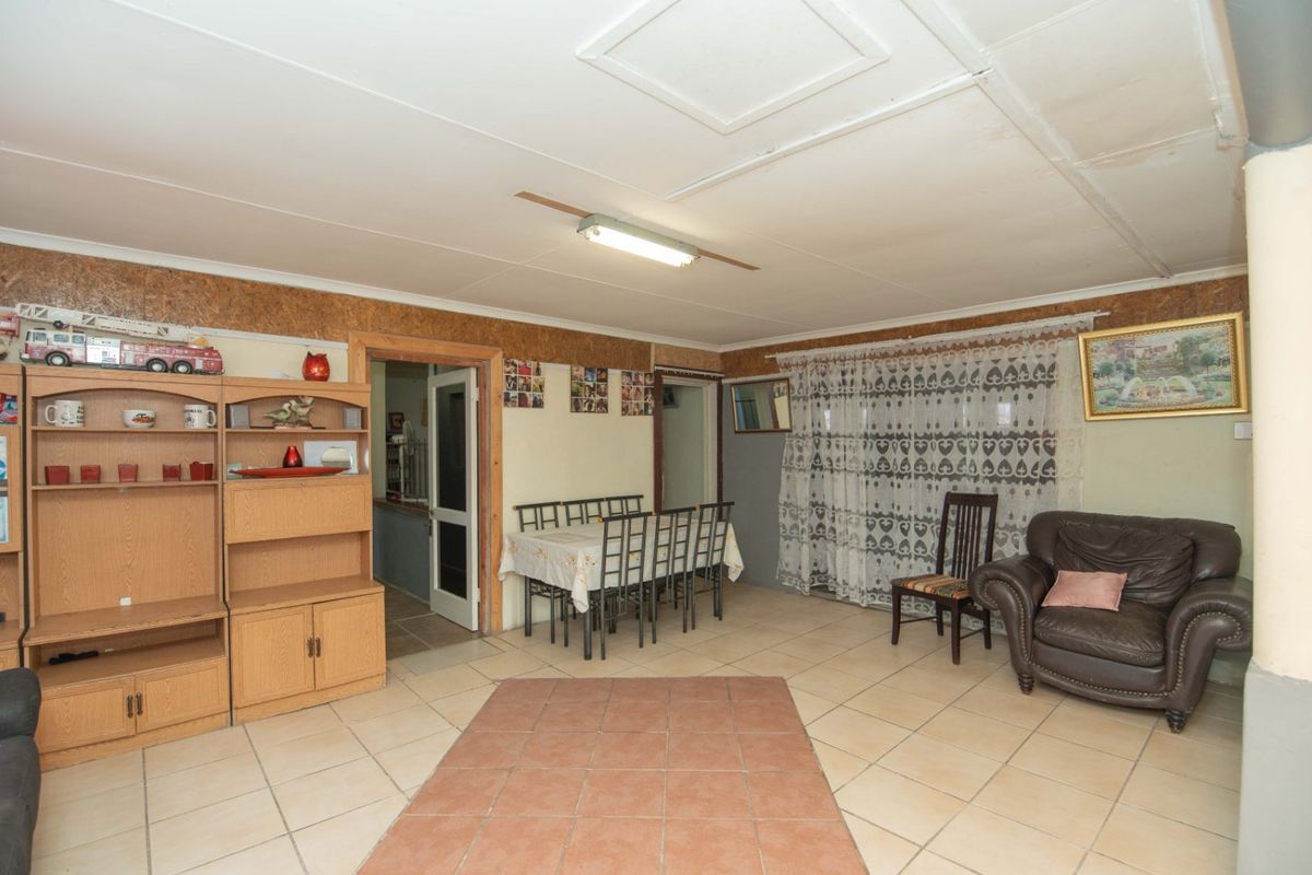 A living area featuring tiled flooring and a ceiling access hatch, requiring cosmetic updates to improve the overall aesthetic and condition of the space.