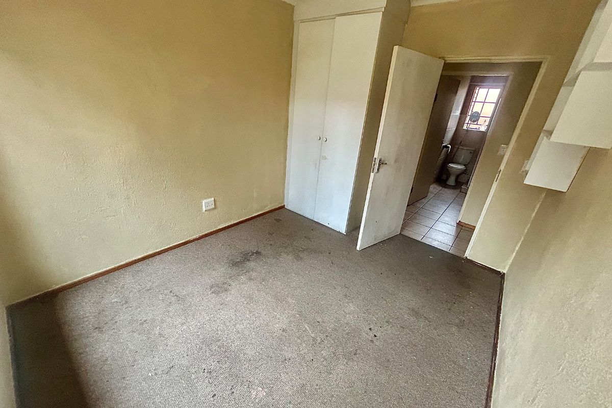 An empty bedroom featuring built-in wardrobe storage, carpet flooring, and direct access to an adjacent bathroom.