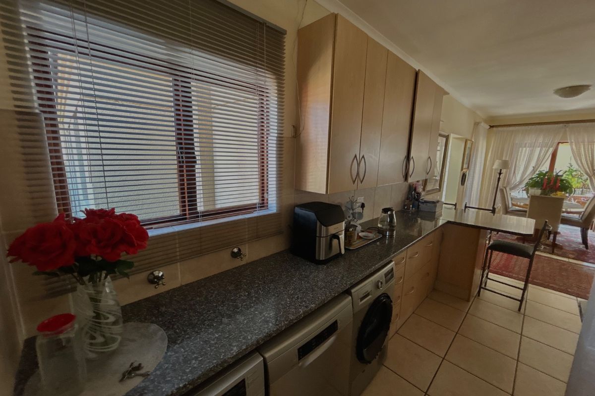 Functional kitchen featuring laminate cabinetry, granite countertops, and tiled flooring, with an open-plan layout flowing into the adjacent dining area.