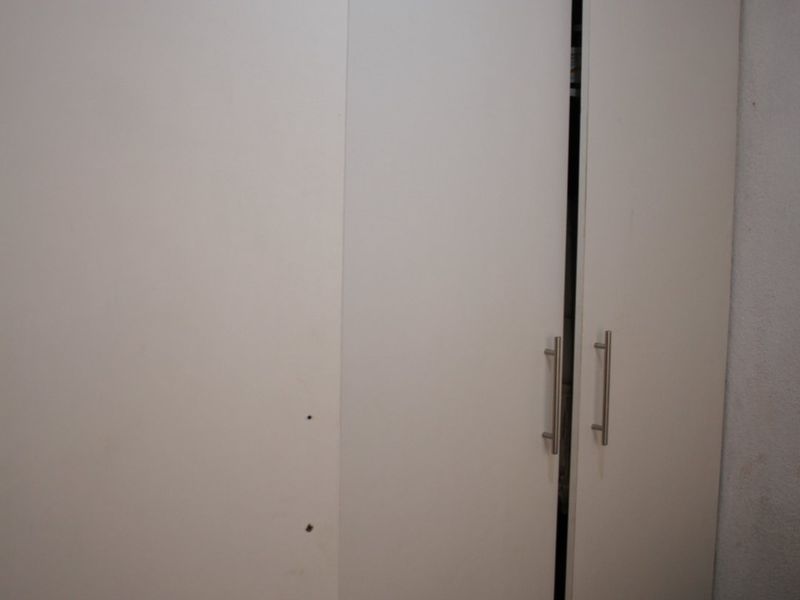 A bedroom featuring a white built-in wardrobe with modern metal handles and decorative ceiling coving.