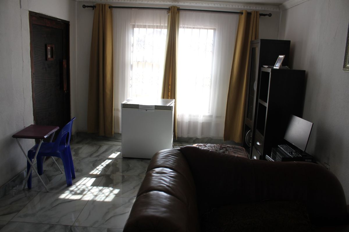 A living room area featuring tiled flooring and decorative cornice, currently used as a multi-purpose space.