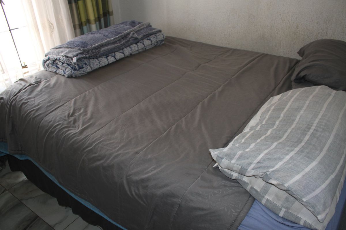 A bedroom featuring tiled flooring and natural light from the adjacent window.