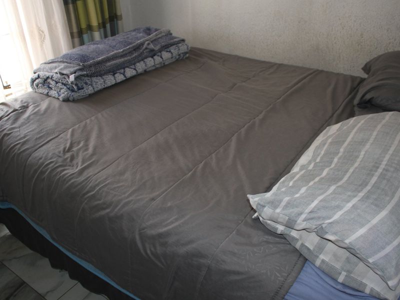 A bedroom featuring tiled flooring and natural light from the adjacent window.