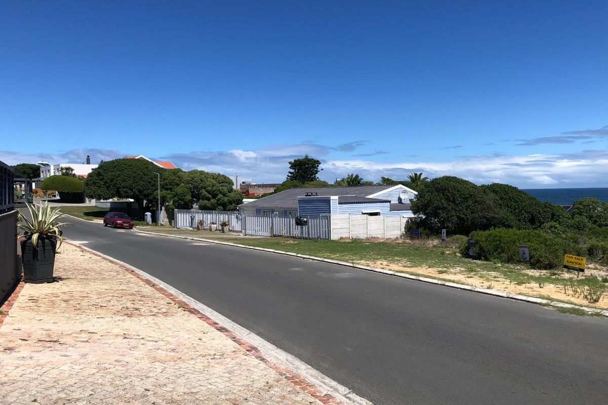 A street-level view of the residential property, showing the road frontage, boundary fencing, and surrounding neighborhood context.
