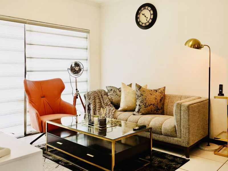 A well-maintained living room featuring tiled flooring and large sliding glass doors with modern roller blinds, providing ample natural light.