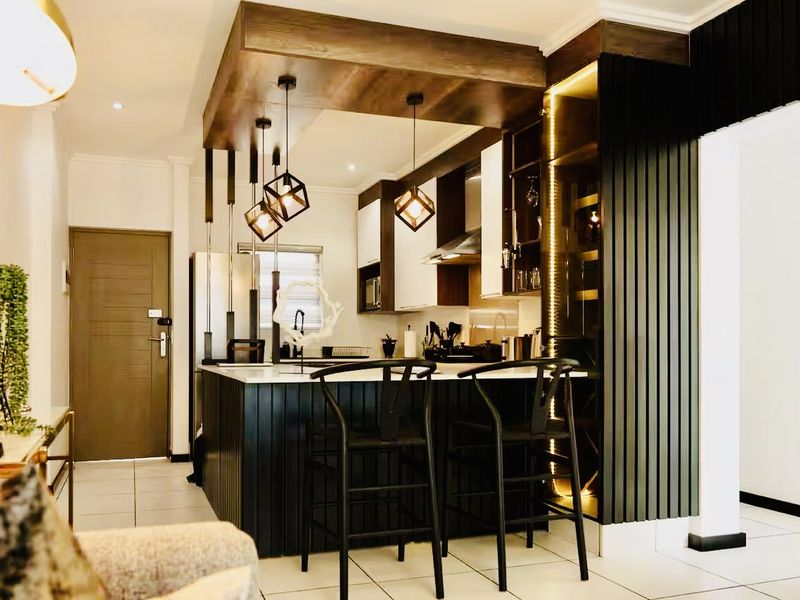 Modern open-plan kitchen featuring a central island, sleek cabinetry, integrated lighting, and stylish slatted wall paneling, creating a sophisticated and functional living space.
