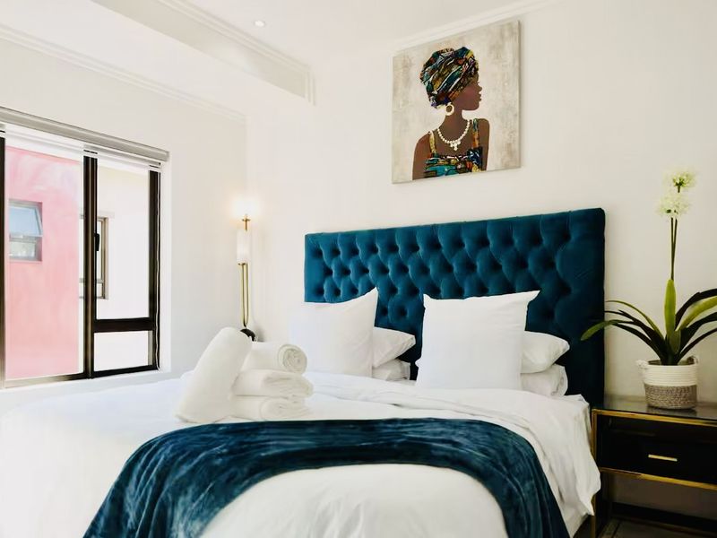 A well-maintained bedroom featuring neutral walls, recessed ceiling lighting, and a large aluminium-framed window providing natural light.