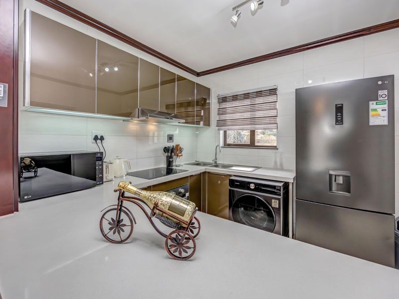 Modern kitchen featuring sleek high-gloss cabinetry, stone countertops, integrated appliances, and a tiled backsplash, offering a clean and functional culinary space.