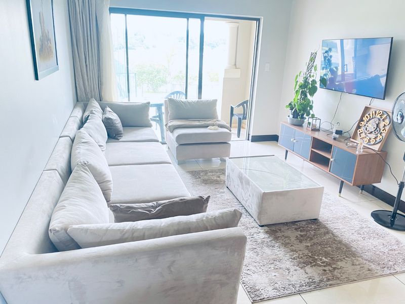A bright living room featuring tiled flooring and large sliding glass doors that provide access to an outdoor balcony area.