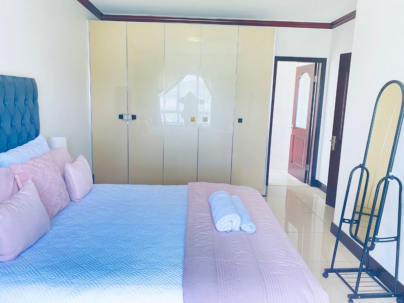A well-maintained bedroom featuring large built-in wardrobes, polished tile flooring, and direct access to an adjoining room.