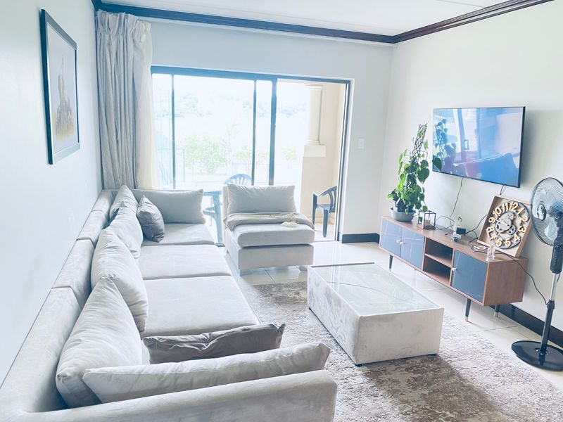 A bright living room featuring tiled flooring, crown molding, and a large sliding glass door providing access to an outdoor balcony area.