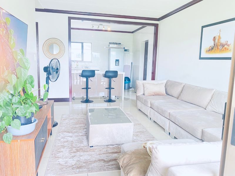 An open-plan living area featuring tiled floors and a connected kitchen with a breakfast bar island.
