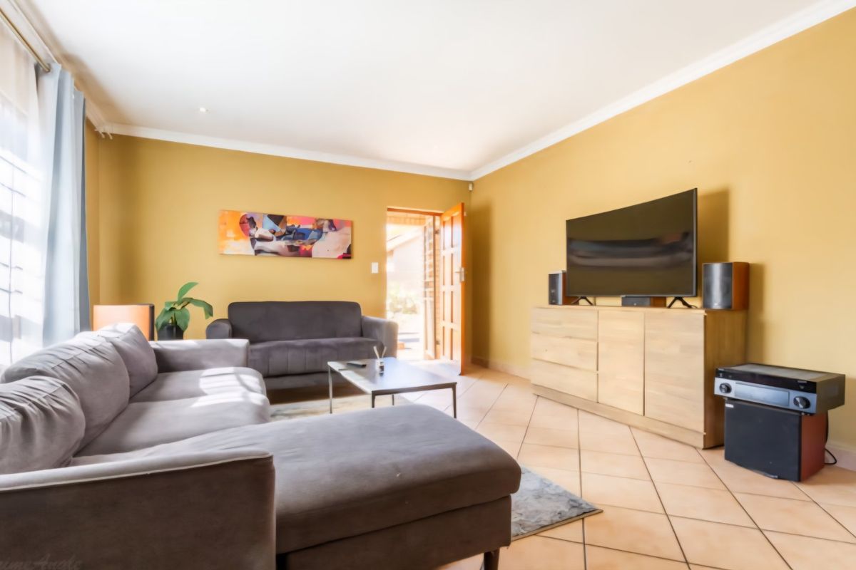 A comfortable living room featuring tiled flooring, recessed downlighting, and direct access to the exterior through a timber door.